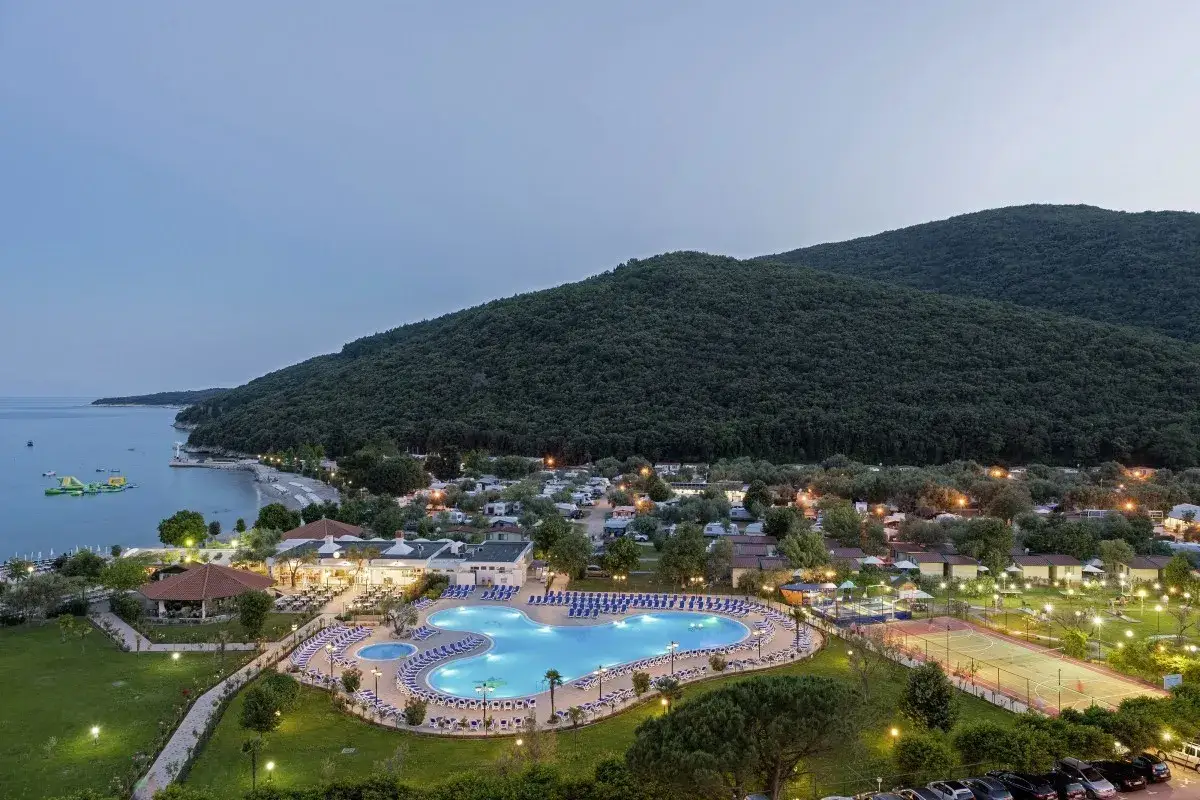 Widok na hotel Narcis w Chorwacji z basenem, kortami i plażą w tle.