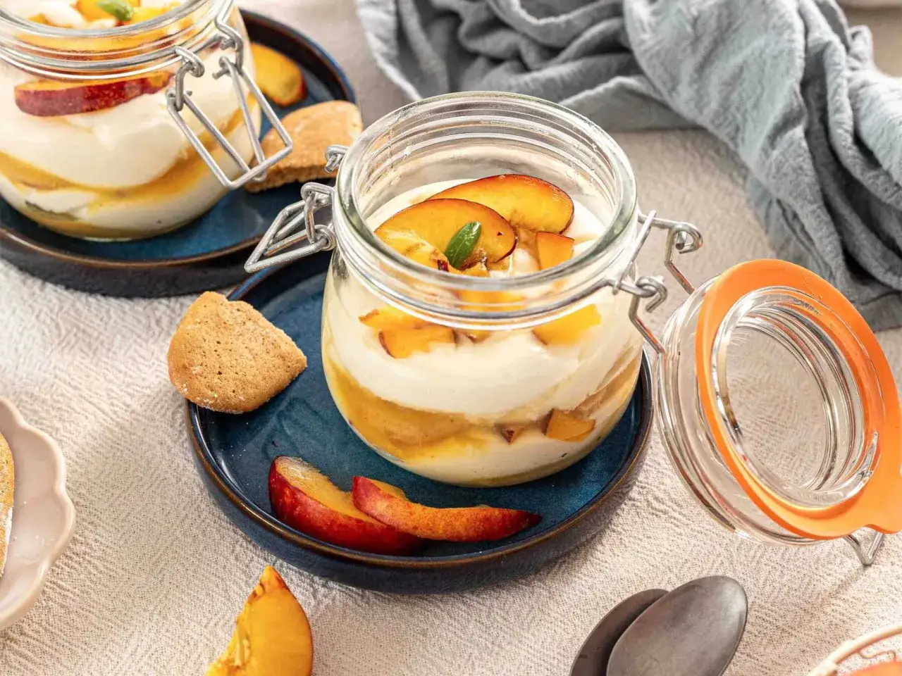 Delizioso tiramis&ugrave; alle pesche in vasetto, con strati cremosi, frutta fresca e biscotti croccanti.