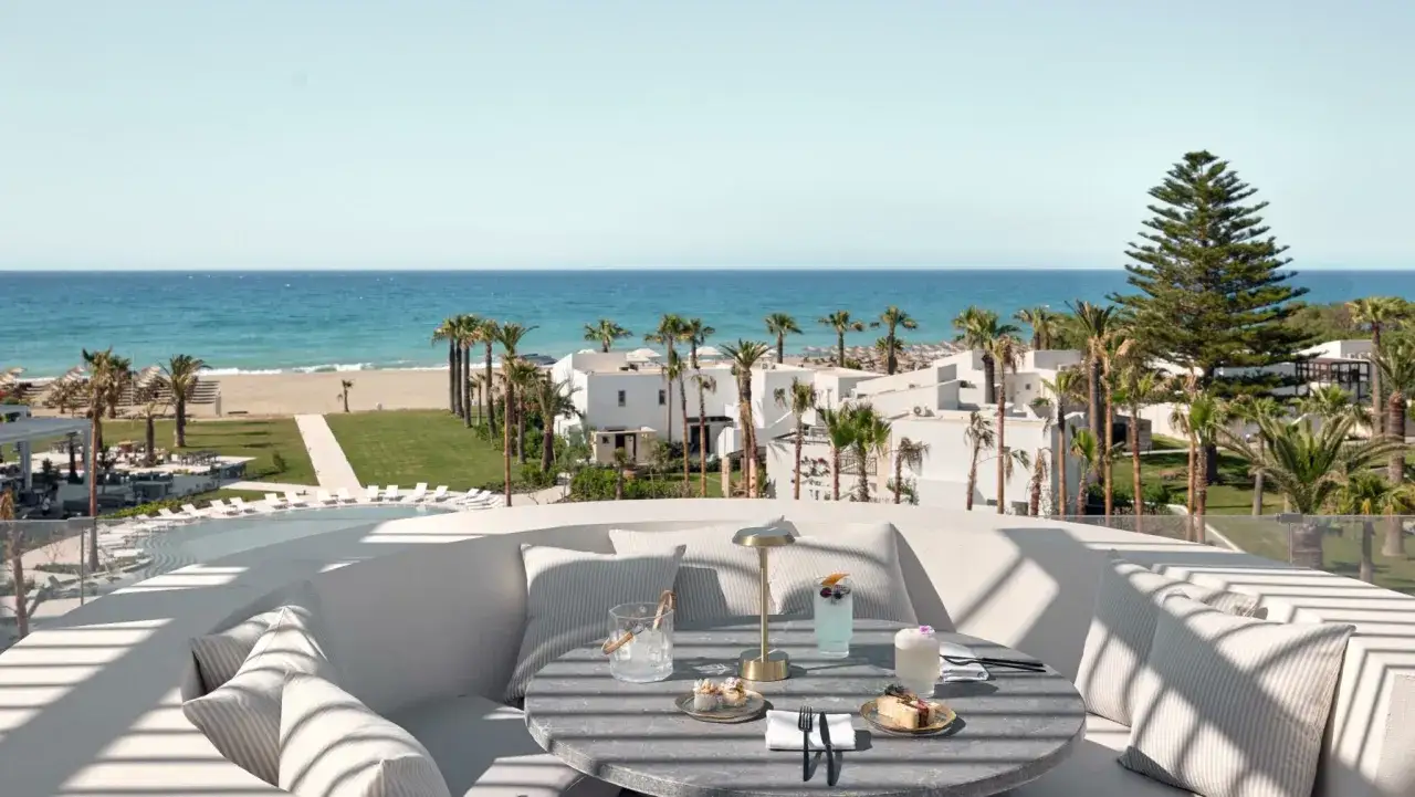 Stolik z drinkami i deserem na tarasie z widokiem na plażę i morze. Idealne miejsce na relaks w ether rooftop bar.