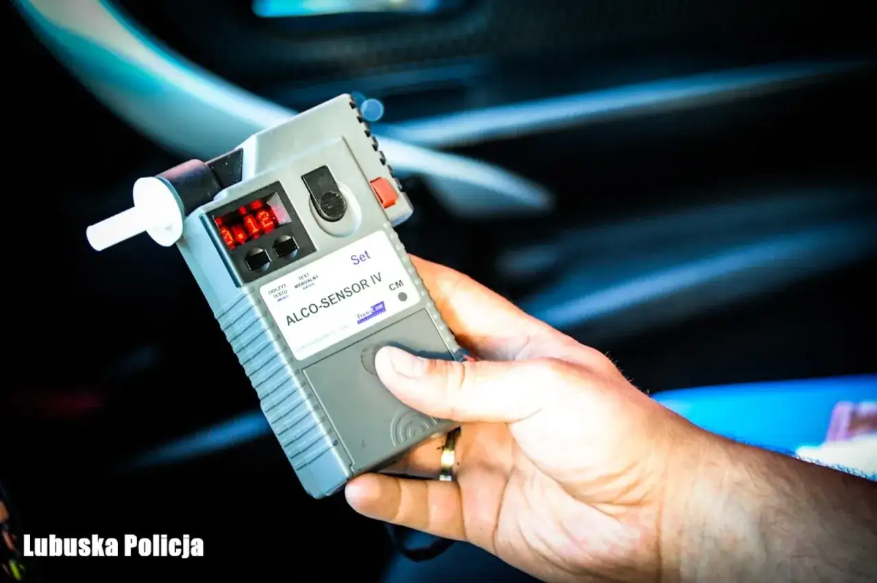 Dłoń trzyma alkomat z wynikiem 0.12 promila alkoholu. Lubuska Policja przypomina o odpowiedzialności.