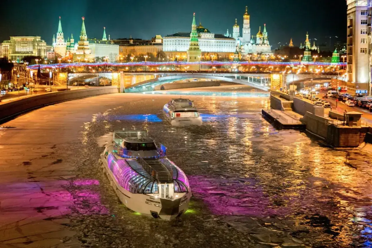 Navi illuminate solcano il fiume ghiacciato di Mosca, la capitale Russia, con il Cremlino sullo sfondo.