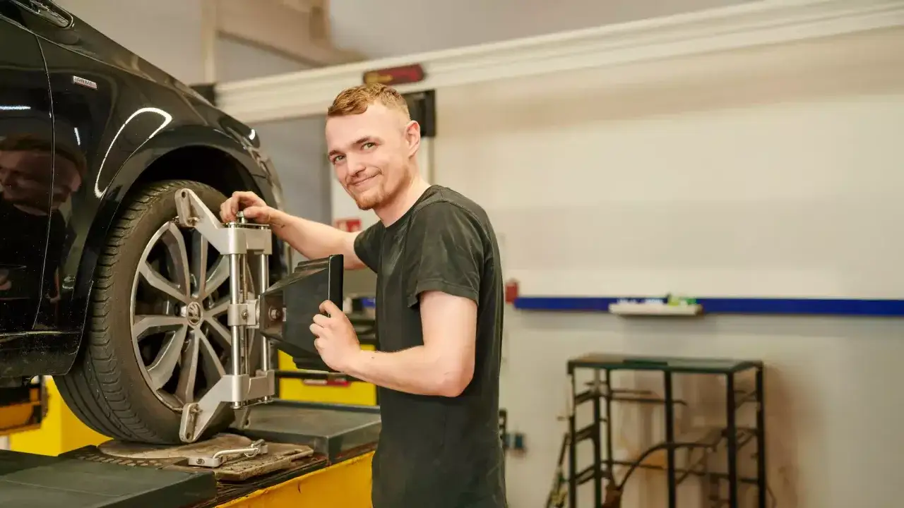 Mechaniker stellt den Sturz am Auto ein.
