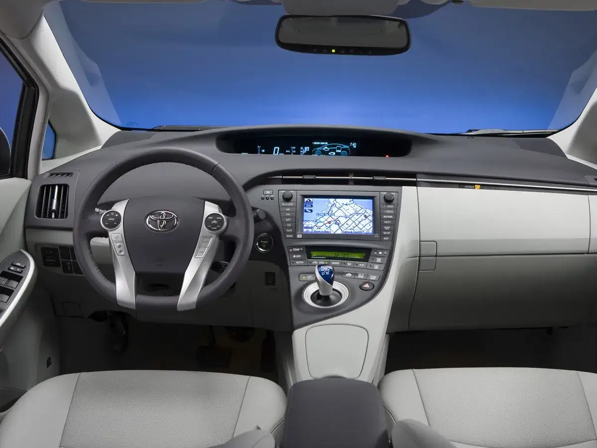 Wnętrze Toyoty Prius, z kierownicą, ekranem nawigacji i siedzeniami. Zastanawiasz się, toyota prius ile miejsc?