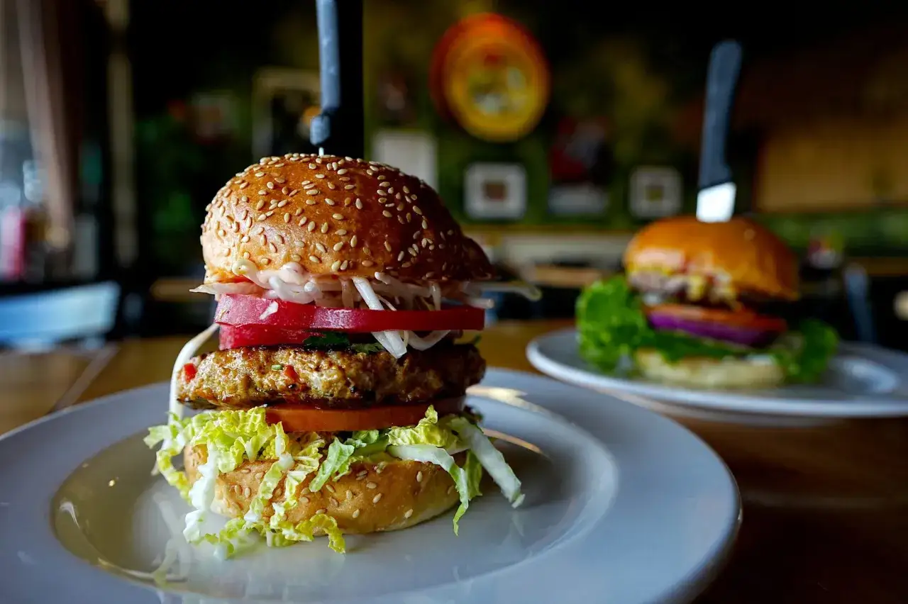 La **champion burger** doble, con lechuga crujiente, tomate jugoso y cebolla, lista para ser devorada.