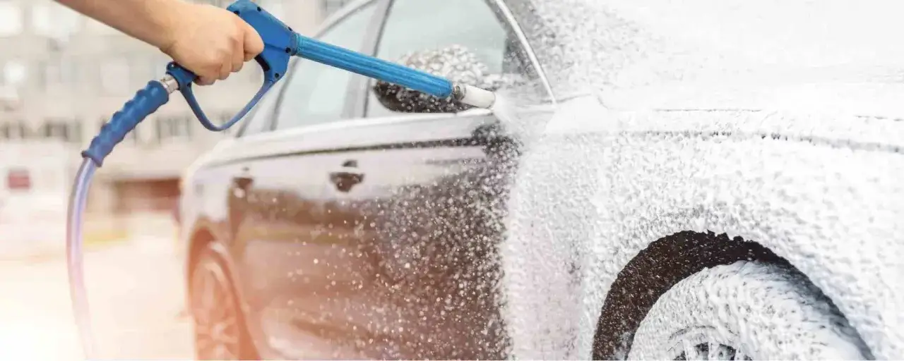En hand sprutar Autoglym Polar Blast-skum p&aring; en bil. Bilen t&auml;cks av ett tjockt lager vitt skum.