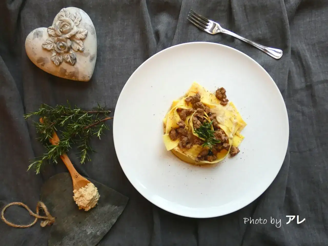 Pappardelle al ragù di anatra, un piatto ricco e saporito, guarnito con rosmarino fresco.