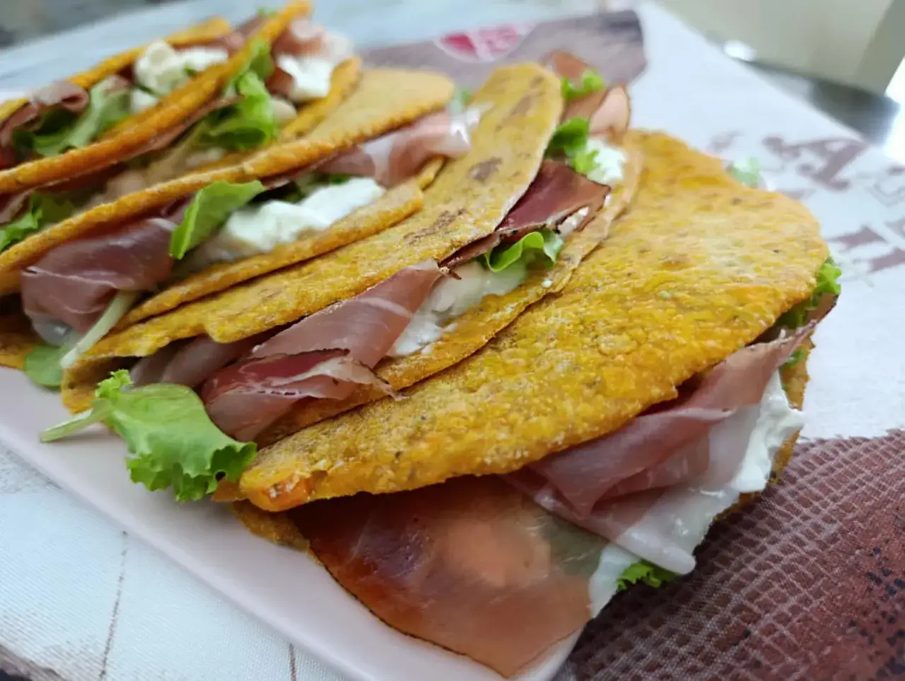 Piadina di carote ripiena di prosciutto crudo, mozzarella e lattuga fresca. Un piatto gustoso e colorato.