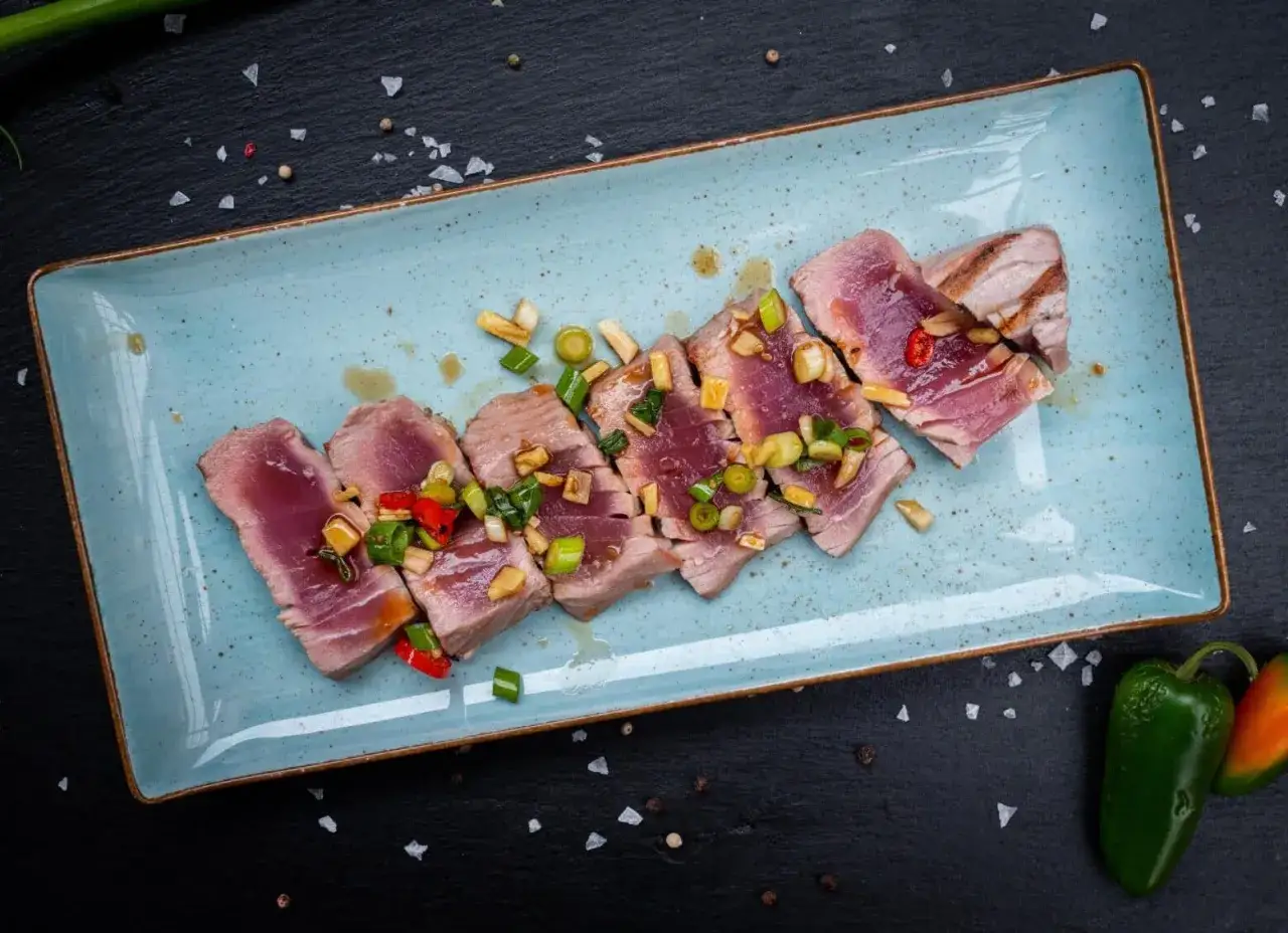 Perfekt gegrillter Thunfisch, in Scheiben geschnitten und mit Frühlingszwiebeln und Chili garniert. Ein Genuss für jeden Fischliebhaber.