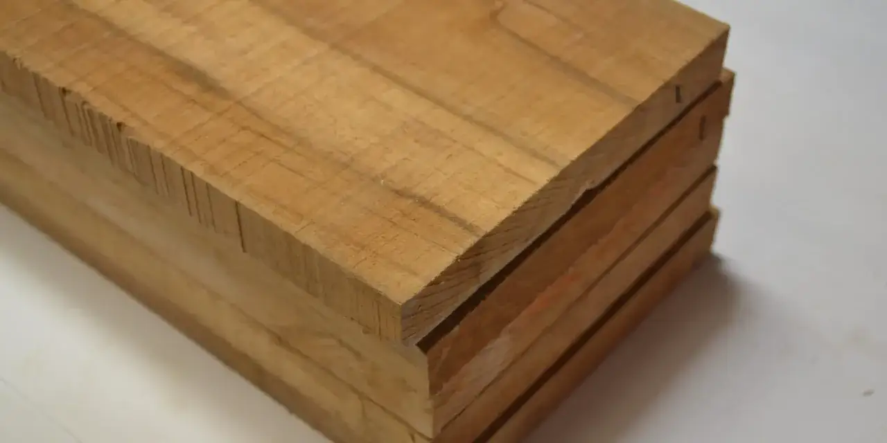 Bloques de madera de tono claro, apilados y listos para ser trabajados. La teca y el ébano son ejemplos de maderas valiosas para la carpintería.
