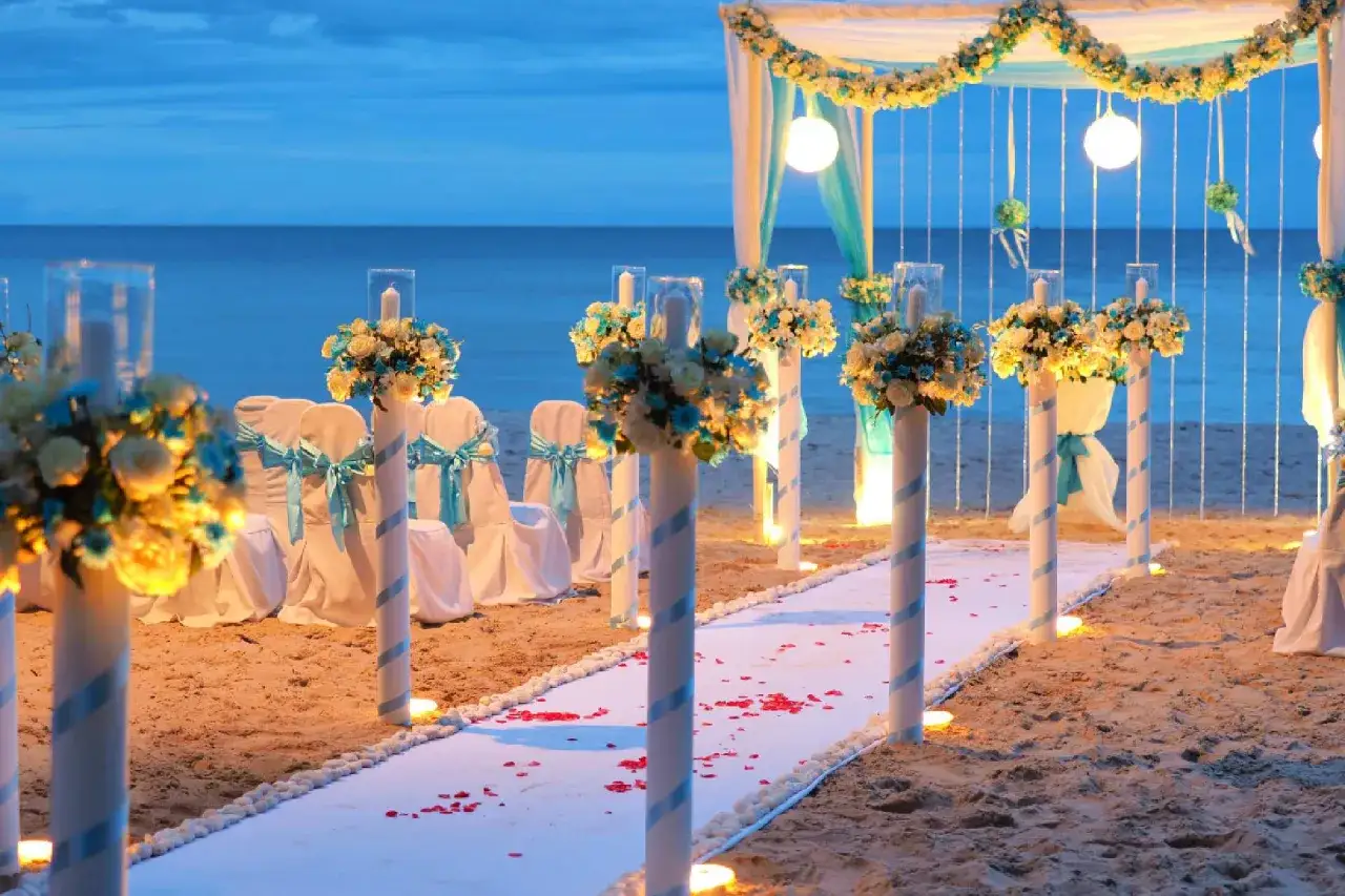 Allestimento romantico per un matrimonio spiaggia, con fiori bianchi e azzurri, candele e sedie decorate.