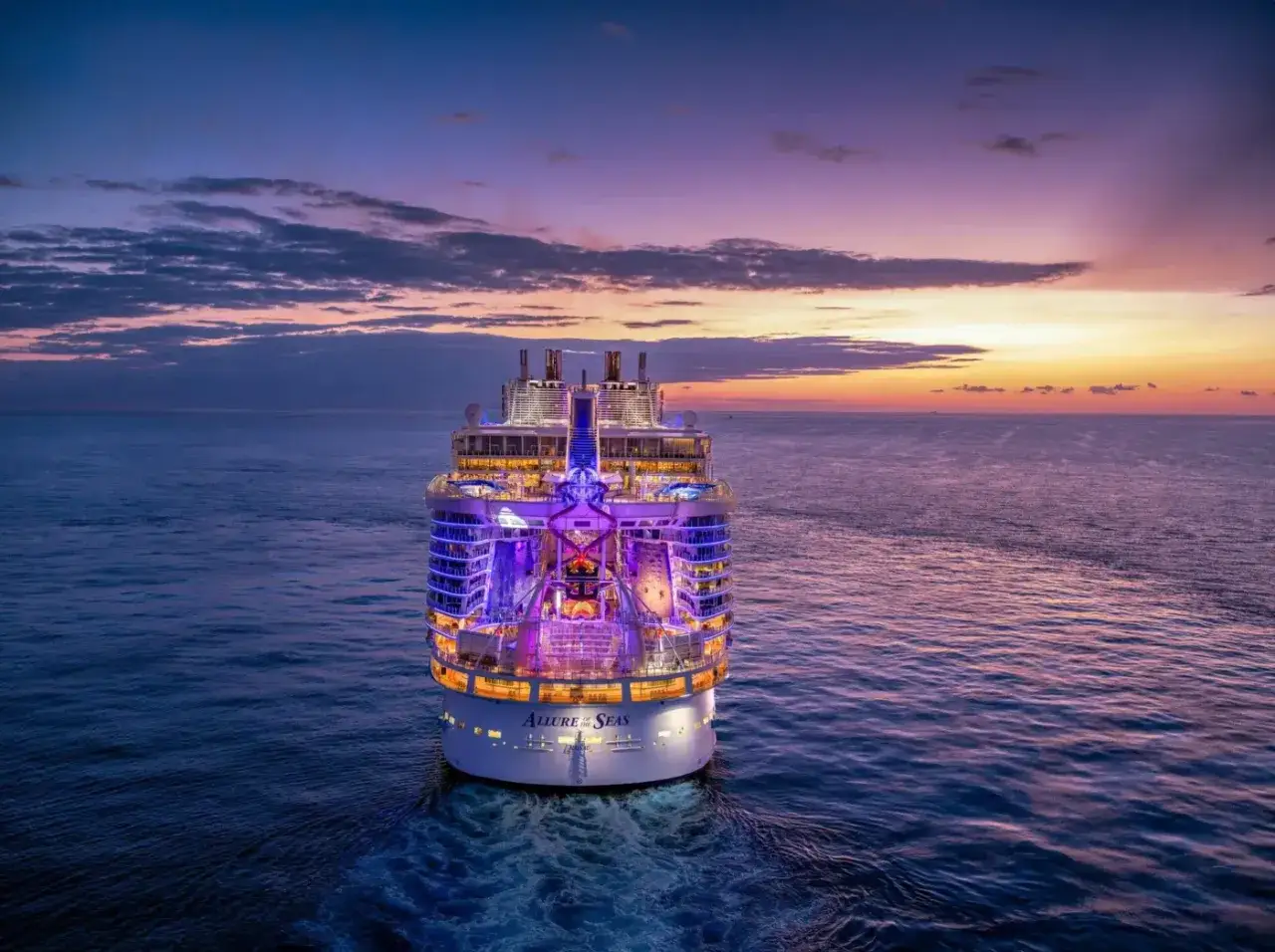 Gigantesca nave da crociera illuminata al tramonto, un sogno per chi si chiede quanto costa una crociera ai Caraibi.