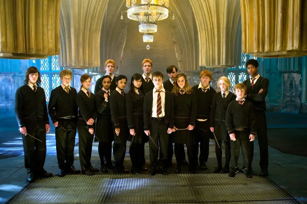 Uczniowie Hogwartu, w tym Harry Potter, stoją w Wielkiej Sali, gotowi na lekcję.