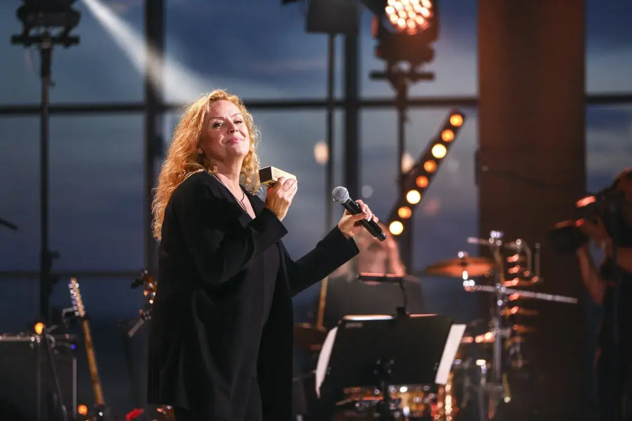 Hanna Banaszak na scenie, z mikrofonem i harmonijką, wykonuje swoje piosenki.