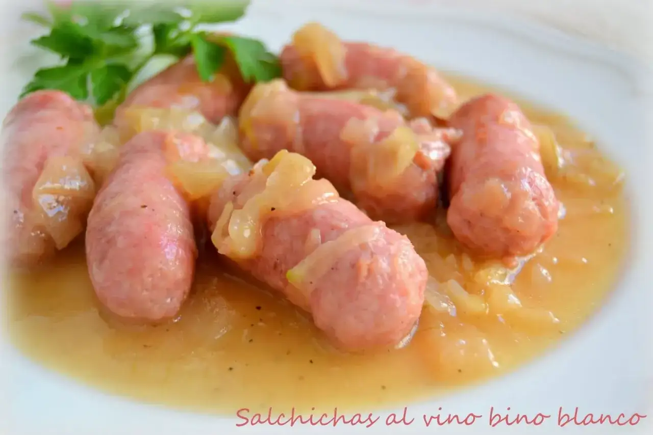 Salchichas al vino blanco, tiernas y jugosas, servidas con cebolla caramelizada en una deliciosa salsa.