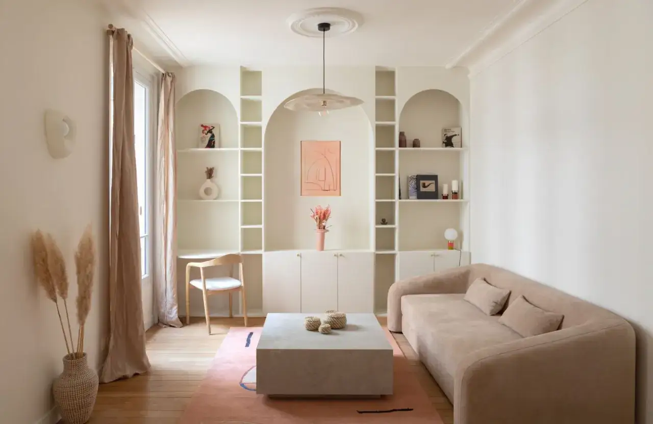 Un bureau discret est int&eacute;gr&eacute; dans une &eacute;tag&egrave;re murale du salon, &agrave; c&ocirc;t&eacute; d'un canap&eacute; beige et d'une table basse rectangulaire.