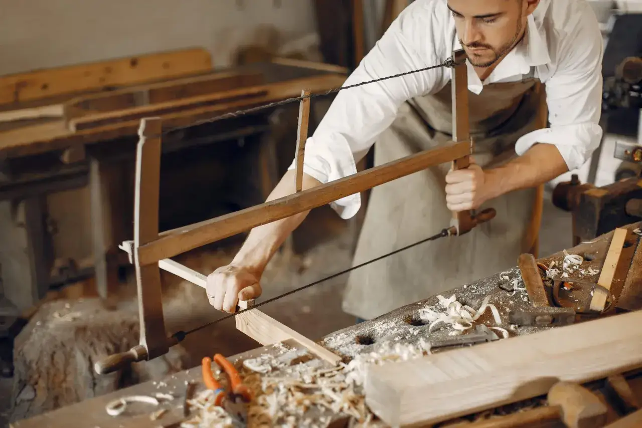 Un artisan utilise une scie pour travailler le bois. Ce métier artistique pourrait être le vôtre si vous aimez créer de vos mains.