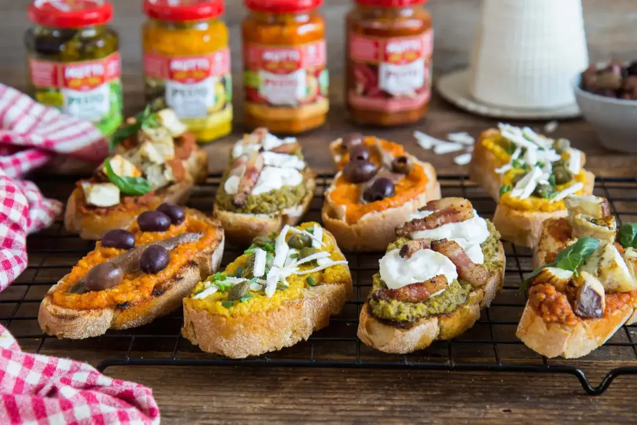 Bunte Bruschetta-Variationen mit Pesto Rosso, Oliven, Sardellen, Käse und Speck.