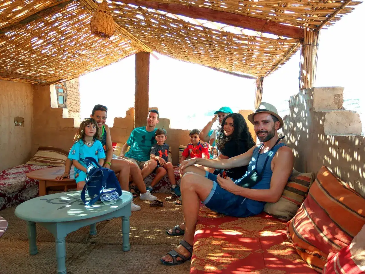 Familia disfrutando de un descanso bajo una sombra tejida, una experiencia aut&eacute;ntica de Marrakech con ni&ntilde;os.