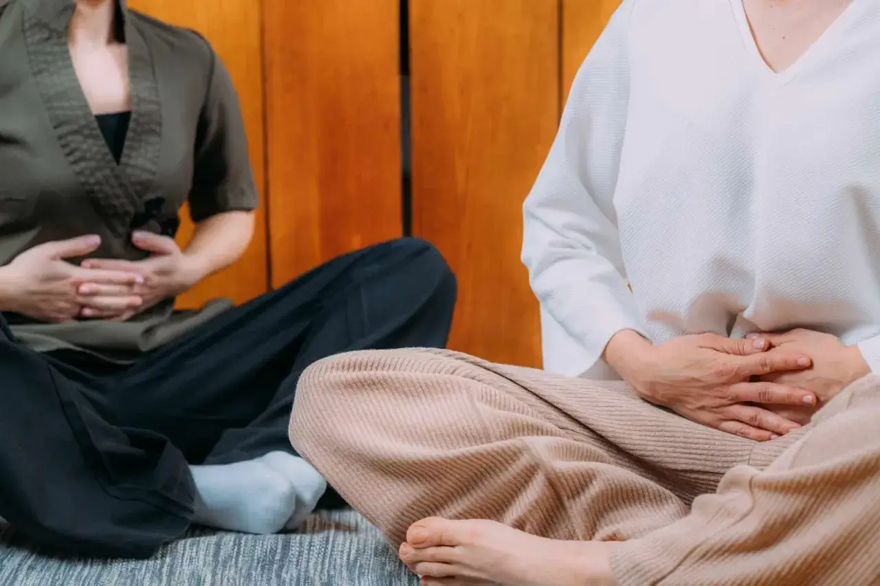 Persone sedute in meditazione, mani sull'addome per favorire lo sblocco diaframma emozioni e il rilassamento.