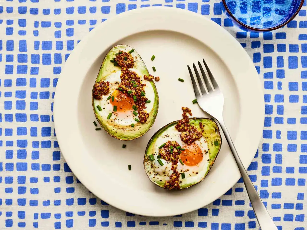 Tv&aring; halvor av bakad avokado med &auml;gg, toppad med senapsfr&ouml;n och gr&auml;sl&ouml;k. Ett enkelt och gott avocado recept.