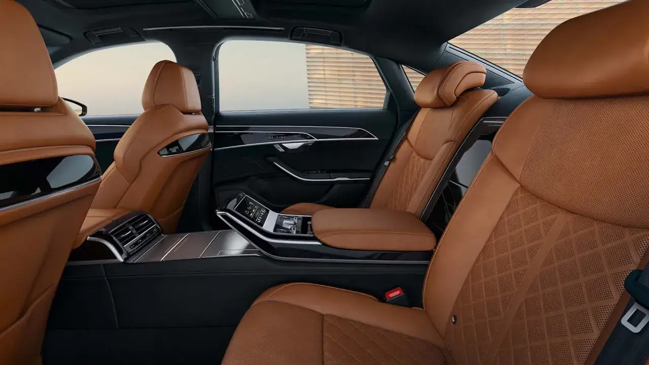 Luksusowe, brązowe skórzane fotele z pikowaniem w stylu romboidalnym w Audi RS8. Widok z tyłu na konsolę środkową i drzwi.