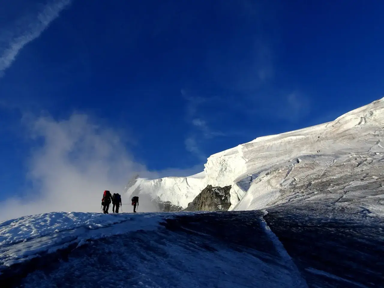 Bergsteiger auf dem Ortler Normalweg, steiler Anstieg im blauen Himmel.