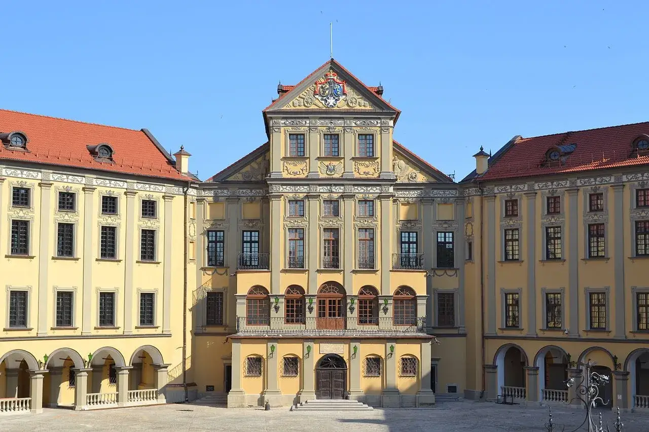 Zamek w Mirze, jedna z głównych atrakcji Białorusi, z żółtą fasadą i czerwonym dachem, w słoneczny dzień.