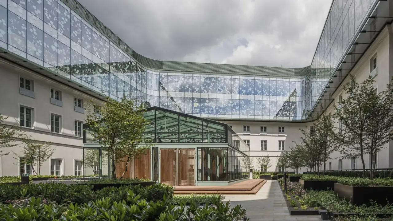 Nowoczesna szklana fasada otacza dawne opactwo, tworząc przestrzeń hotelową i kulturalną. Skutki rewitalizacji są widoczne w harmonijnym połączeniu historii i nowoczesności.