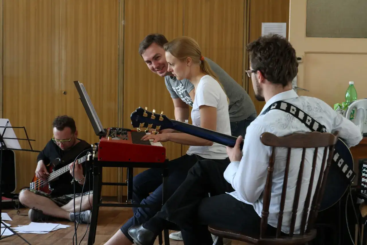 Zesp&oacute;ł ćwiczy, szukając fajna nazwa dla zespołu muzycznego. Klawiszowiec gra, basista i gitarzysta czekają na swoją kolej.