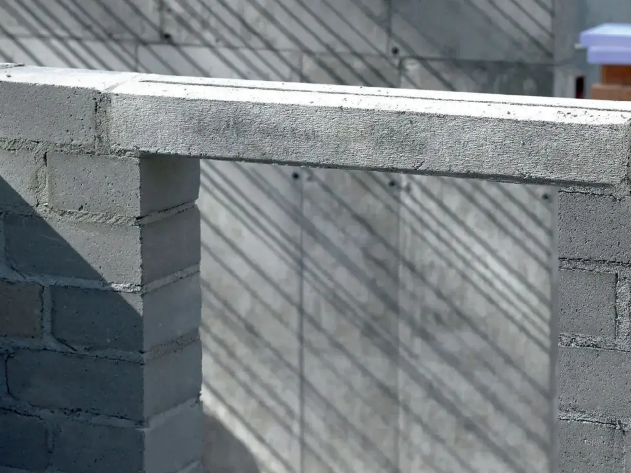 Betonowy nadproże nad otworem w budowie. Cienie padają na ścianę z bloczków.