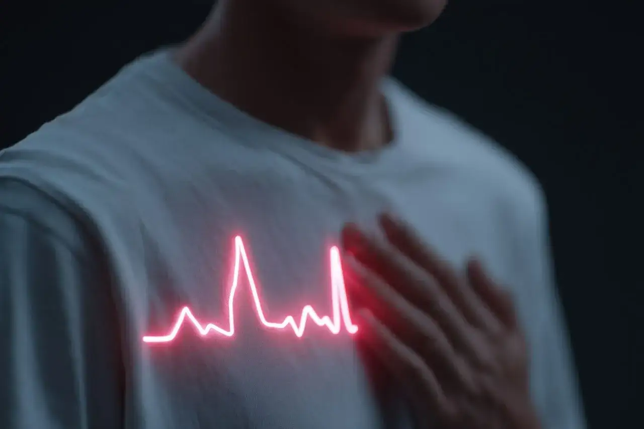 Osoba z dłonią na piersi, na której widnieje neonowy wykres EKG symbolizujący wysoki puls.
