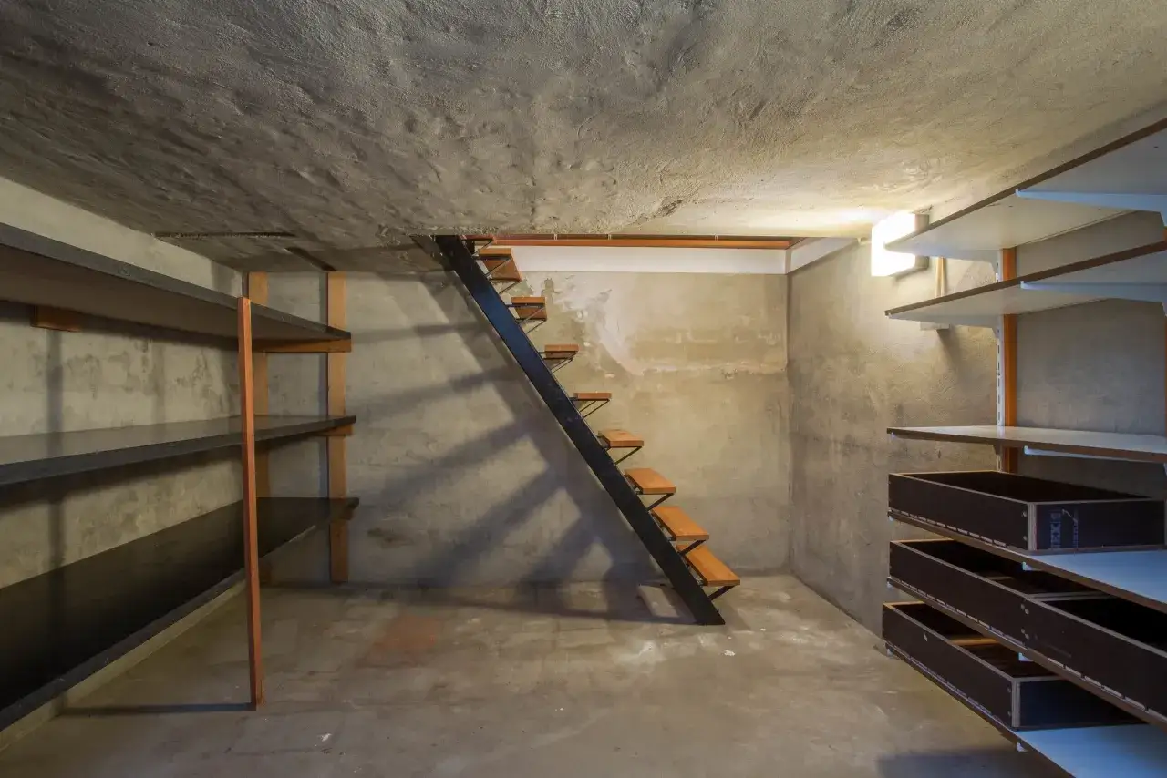 Sótano con estanterías y escalera. Un lugar donde podría acumularse el radón, un gas invisible y peligroso.