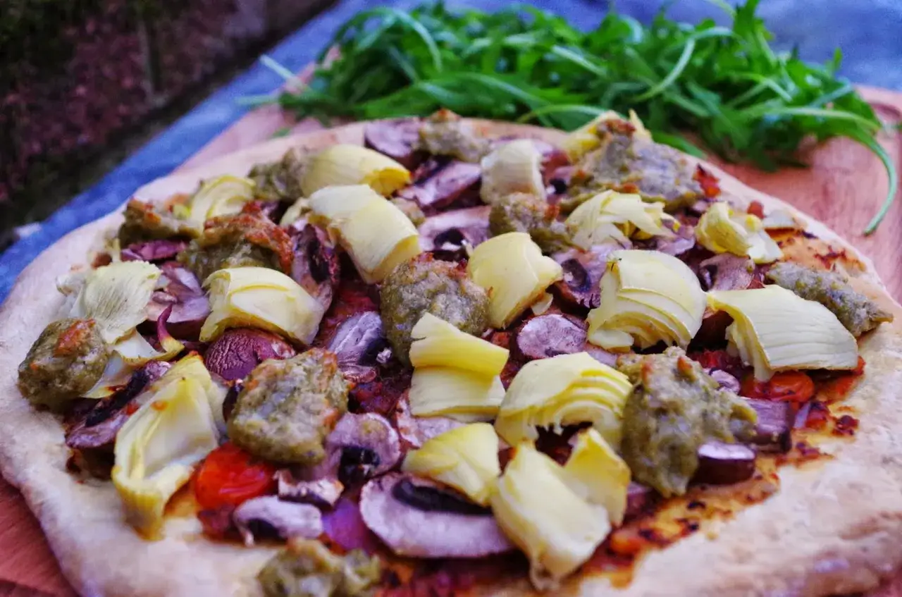 En läcker vegetarisk pizza med kronärtskocka, champinjoner och gröna blad.