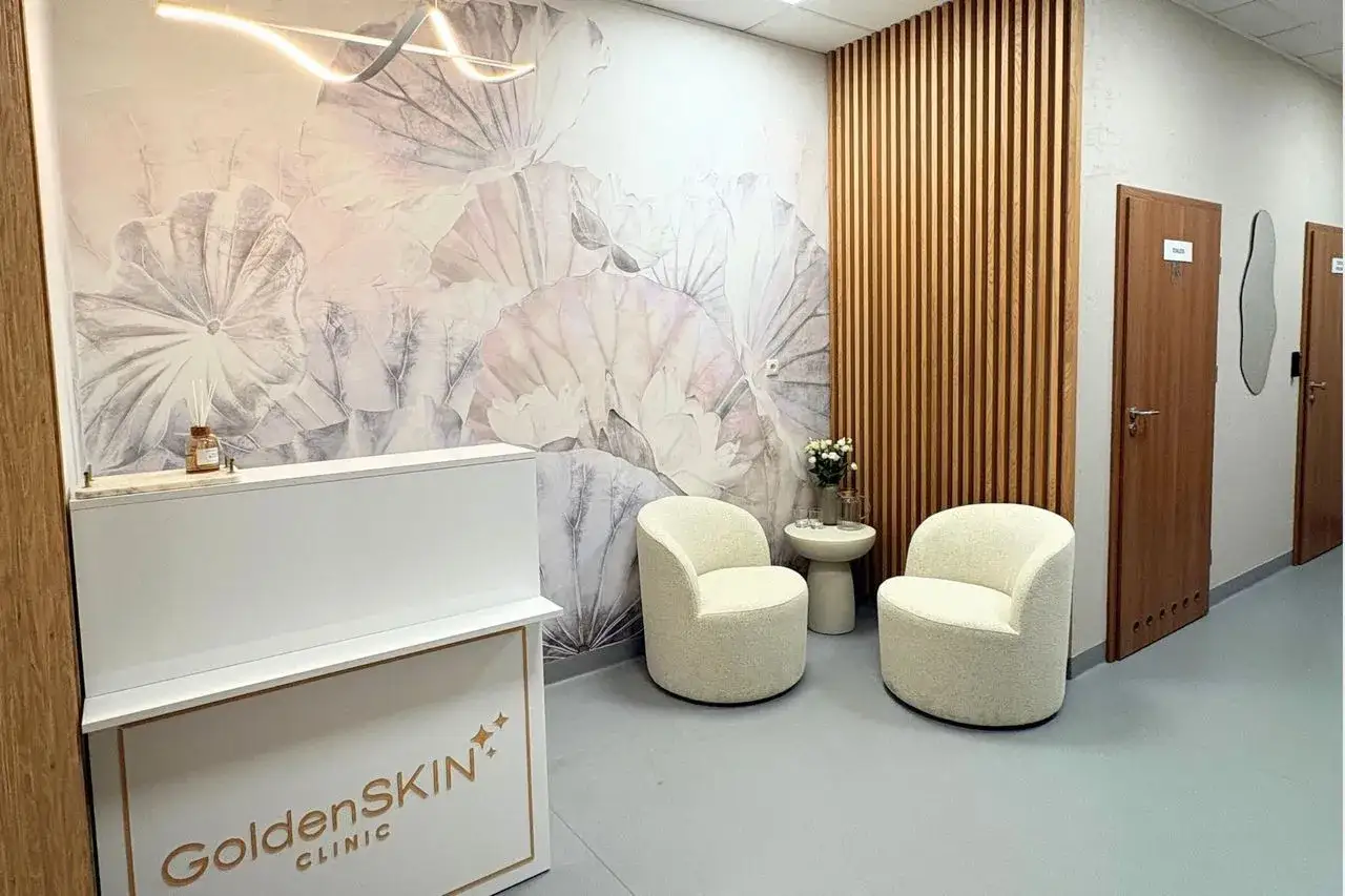 Recepcja kliniki GoldenSkin z fotelem i kwiatami na tle tapety z motywem liści.