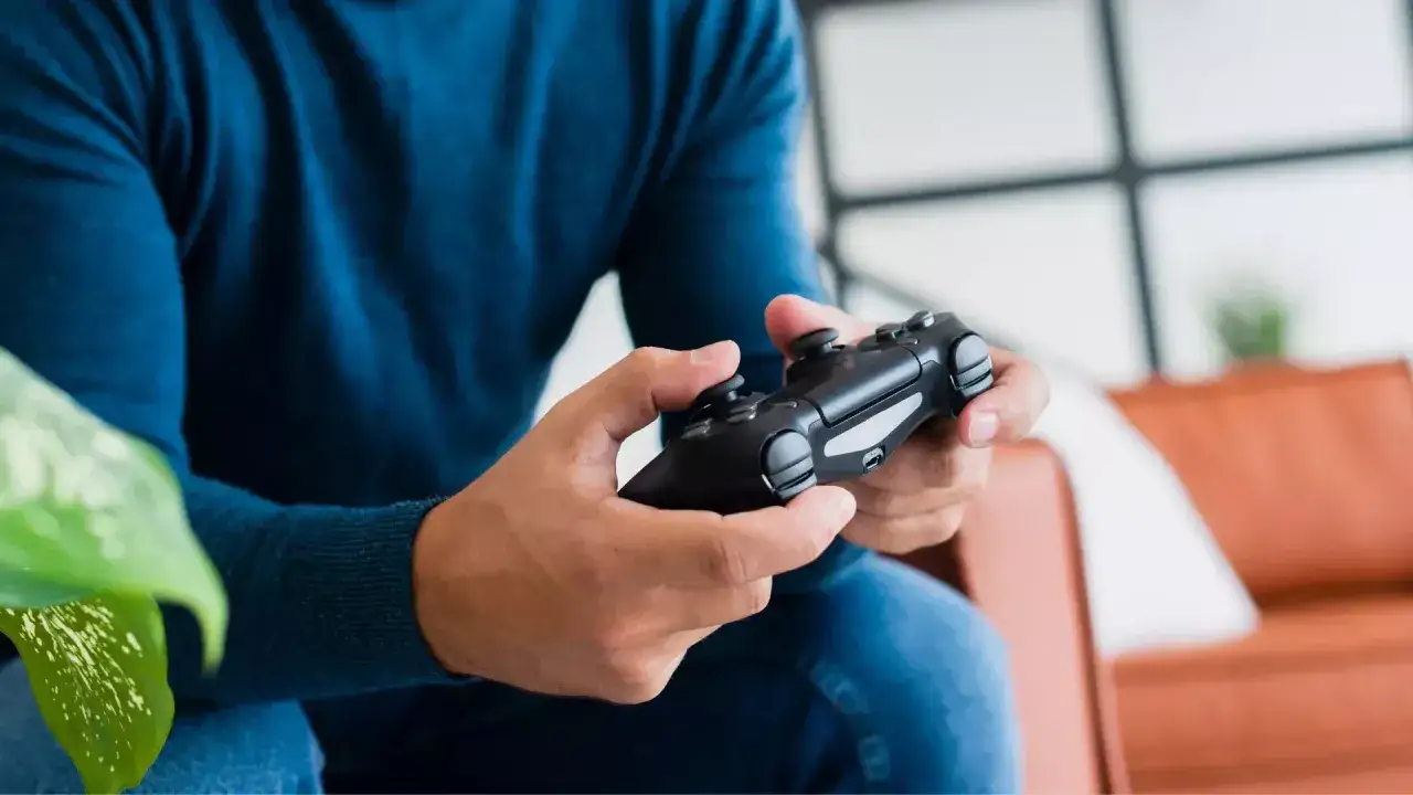 Gracz trzyma pad od PS4, zastanawiając się, jak podłączyć pada PS4 do PS5, by cieszyć się grami.