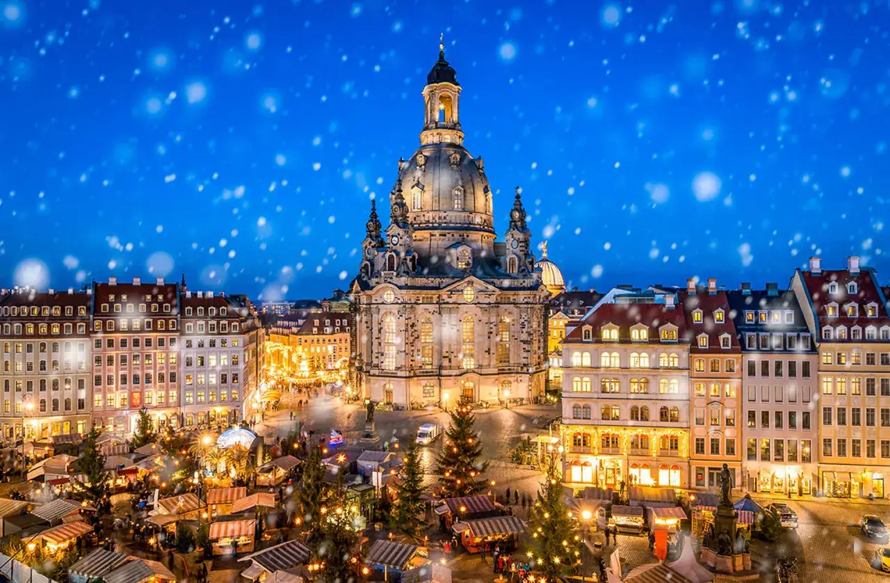 Beleuchteter Weihnachtsmarkt vor der Frauenkirche im Schnee. Ein magischer Anblick, der die Vorfreude auf Silvester steigert.