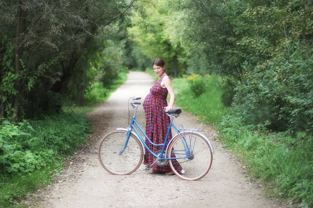 Schwangerschaft und Fahrrad fahren: Eine werdende Mutter steht mit ihrem Fahrrad auf einem Waldweg.