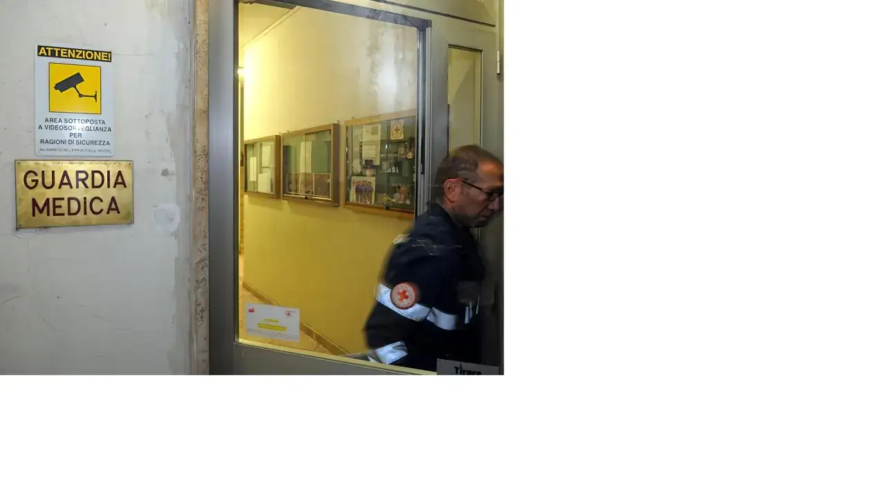 La guardia medica si paga. Un uomo in divisa entra nella struttura, segnalata da un cartello.