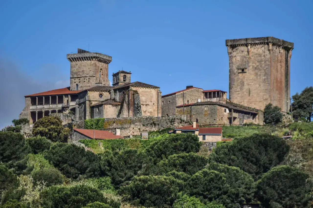 Impresionante conjunto de torres y edificios de piedra en una colina verde. Un lugar ideal que ver en Verín para sentir la historia.