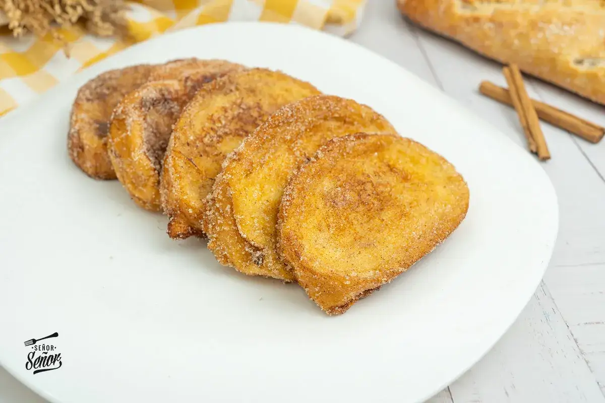 Torrijas doradas y crujientes, recién hechas en freidora de aire, espolvoreadas con azúcar y canela.