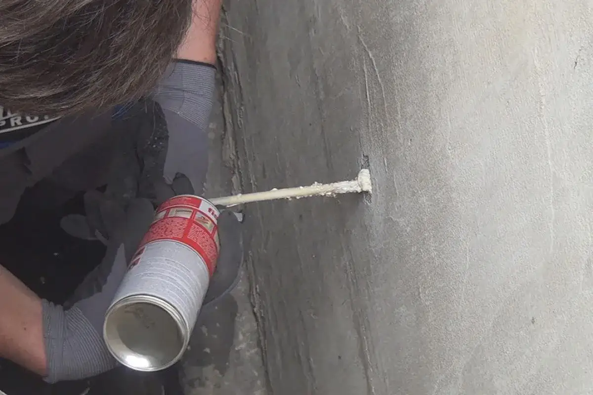 Mit Montageschaum wird ein kleines Bohrloch in der Wand abgedichtet.