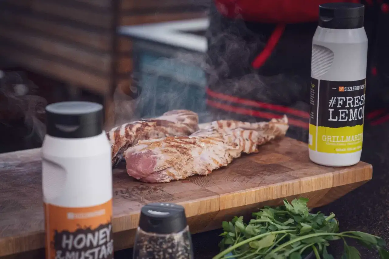 Heißes schweinefilet im ofen, dampfend auf einem Holzbrett. Daneben Saucen und Kräuter. Wie lange im Ofen?