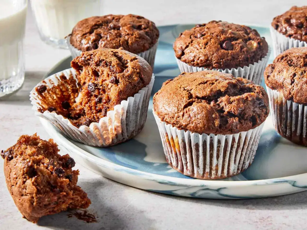 Saftige schoko bananen muffins mit Schokost&uuml;ckchen, einer davon angeknabbert. Daneben ein Glas Milch.
