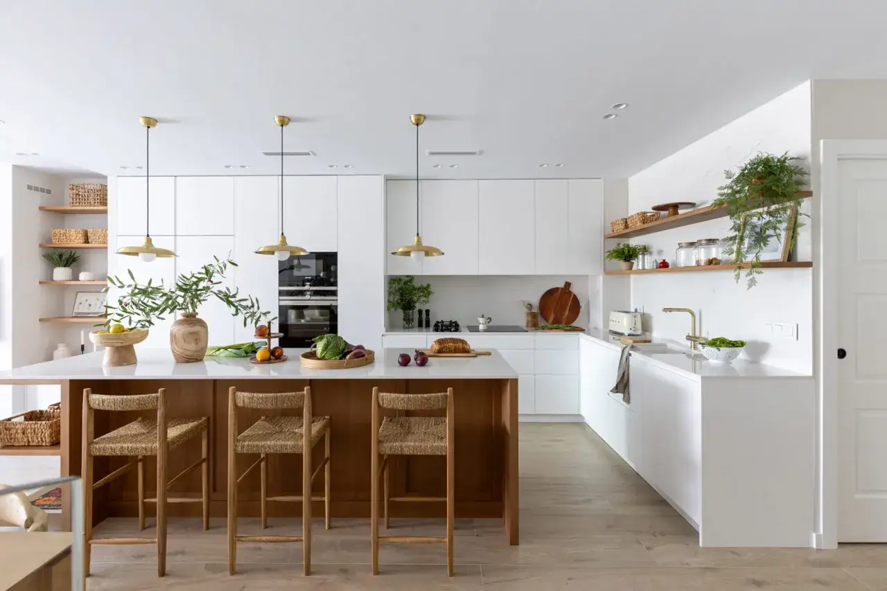 Cocina moderna y luminosa, un espacio de **interior design studio** con isla central de madera, taburetes de fibras naturales y electrodomésticos integrados.