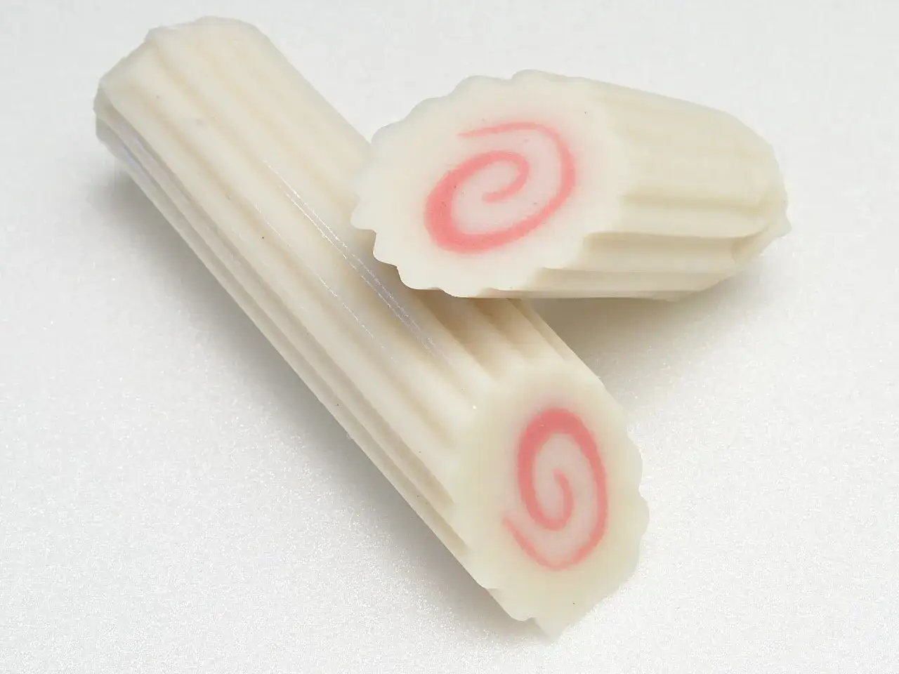 Białe rolki z różową spiralą w środku. To narutomaki, popularny dodatek do ramenu.