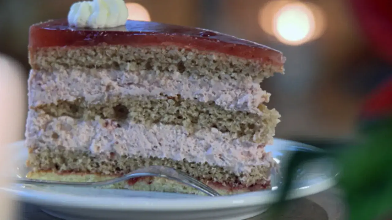 Ein Stück Buchweizentorte mit Preiselbeeren und einer Geleeschicht, garniert mit Sahne.