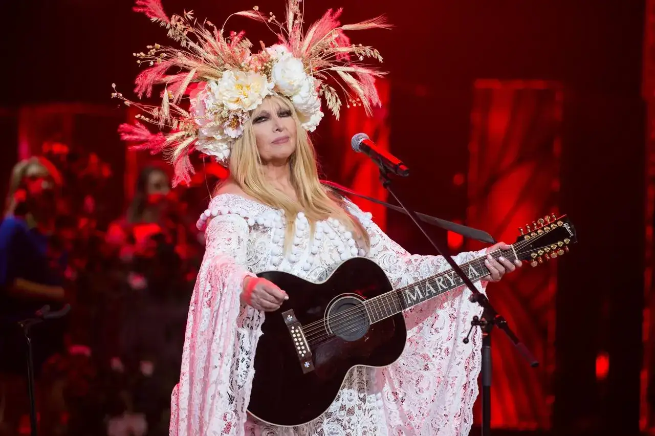 Maryla Rodowicz w koronkowej kreacji i kwiecistym wianku gra na gitarze. Ile lat ma Maryla Rodowicz? Tego nie wiemy, ale wciąż zachwyca na scenie.