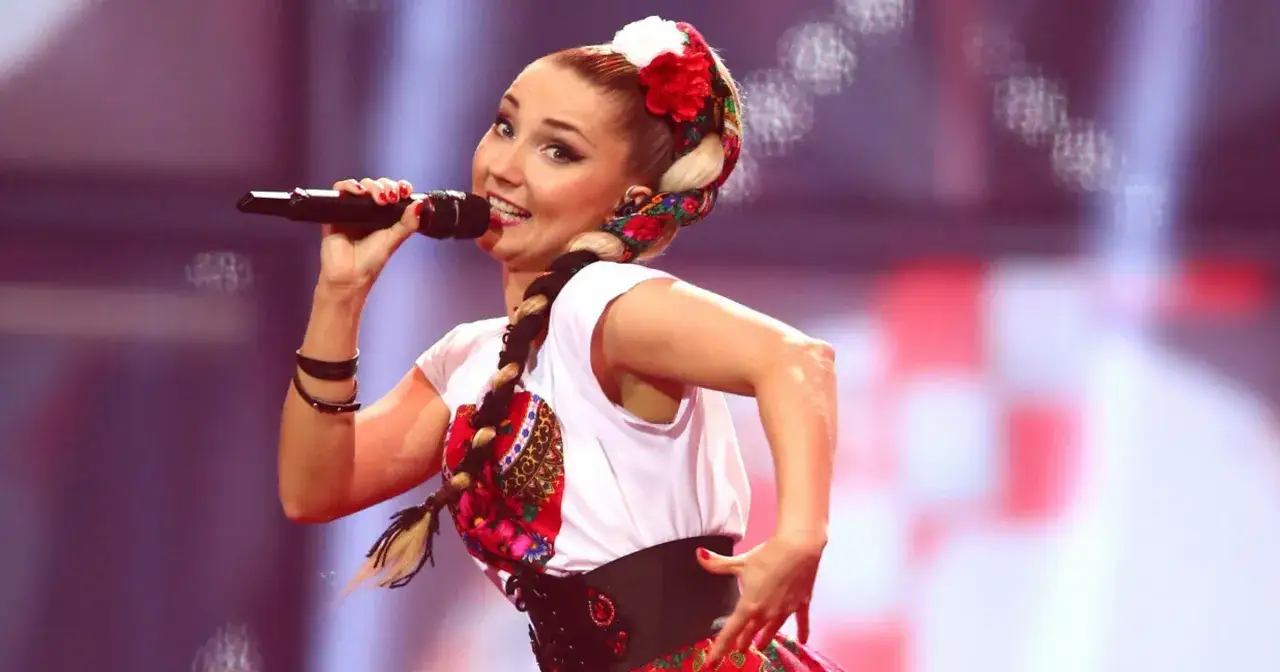 Cleo w narodowym stroju na Eurowizji, śpiewa z pasją, warkocz ozdobiony chustą.