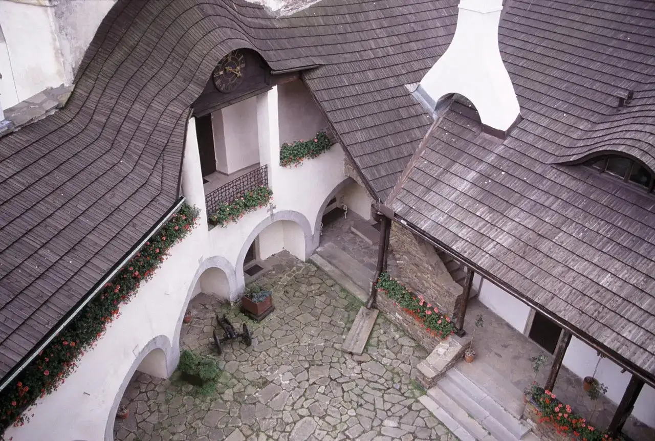 Dziedziniec zamku w Niedzicy z kamienną posadzką, arkadami i drewnianymi dachami. Sprawdź zamek w Niedzicy cennik, by zaplanować wizytę.