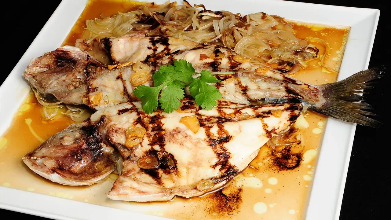 Dorada a la espalda, jugosa y a la parrilla, con l&aacute;minas de ajo y cebolla caramelizada, servida en salsa dorada.